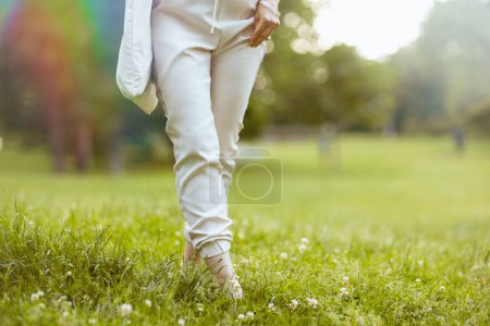 Téléchargez les photos : L'heure d'été. Gros plan sur la femme marchant dans la prairie dans le parc de la ville. - en image libre de droit