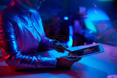 Téléchargez les photos : Neon metaverse concept futuriste. Gros plan sur la femme en utilisant la tablette PC au bureau. - en image libre de droit