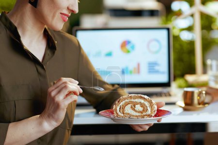 Photo for Closeup on modern business woman with laptop, piece of cake and cup of coffee in modern office. - Royalty Free Image