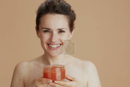 Foto de Retrato de mujer moderna feliz con exfoliante facial aislado sobre fondo beige. - Imagen libre de derechos
