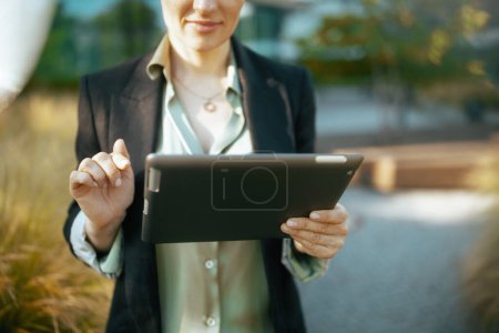 Foto de Primer plano de la mujer de mediana edad empleada en el distrito de negocios en chaqueta negra usando tableta PC. - Imagen libre de derechos