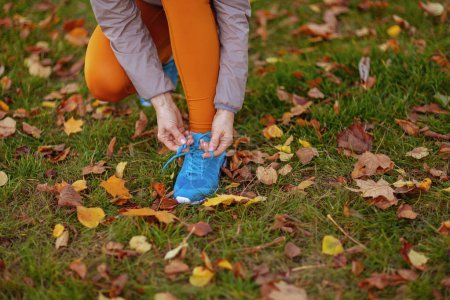 Photo for Hello autumn. Closeup on woman in fitness clothes in the park tying shoelaces. - Royalty Free Image