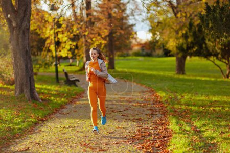 Foto de Hola otoño. mujer joven en ropa de fitness en el parque corriendo. - Imagen libre de derechos