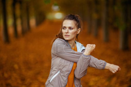 Photo for Hello autumn. trendy woman in fitness clothes in the park stretching. - Royalty Free Image