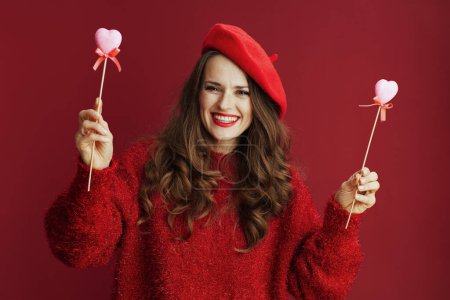 Foto de Feliz San Valentín. sonriente mujer moderna de 40 años en suéter rojo y boina con corazones en palo. - Imagen libre de derechos