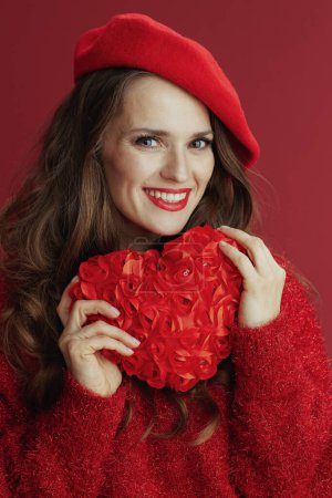 Foto de Feliz San Valentín. sonriente elegante mujer de mediana edad en suéter rojo y boina con corazón rojo. - Imagen libre de derechos