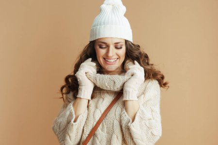 Foto de Hola invierno. mujer elegante sonriente en suéter beige, mitones y sombrero aislados sobre fondo beige. - Imagen libre de derechos