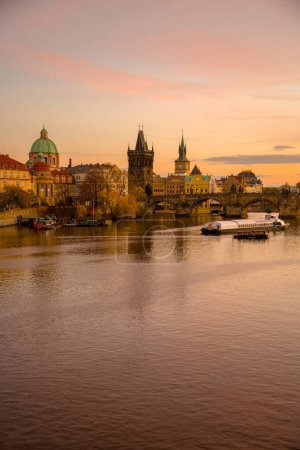 Téléchargez les photos : Paysage avec rivière Vltava, Karlov most et bateau au coucher du soleil en automne à Prague, République tchèque. - en image libre de droit