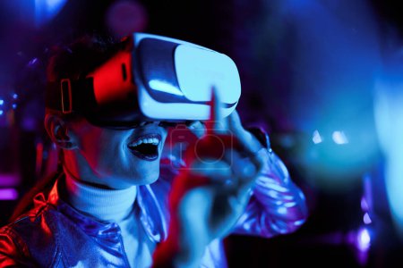 Téléchargez les photos : Neon metaverse concept futuriste. excité élégant 40 ans femme en vr casque tester la réalité virtuelle. - en image libre de droit