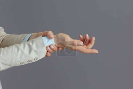 Photo for Closeup on small business owner woman in a light business suit with carpal tunnel syndrome against grey background. - Royalty Free Image
