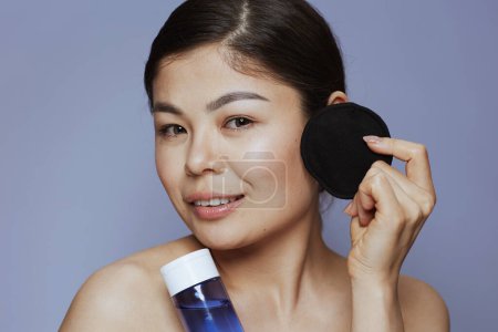 Téléchargez les photos : Femme asiatique moderne avec démaquillant et coton noir sur fond bleu. - en image libre de droit