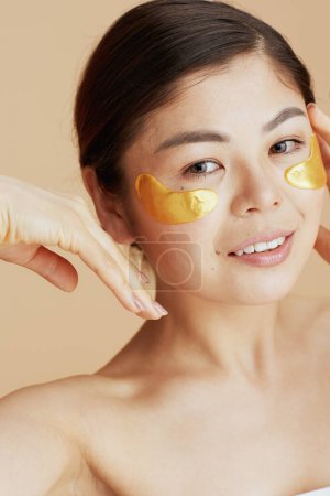 Téléchargez les photos : Jeune femme avec des patchs pour les yeux sur fond beige. - en image libre de droit