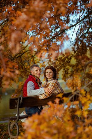 Foto de Hola otoño. feliz pareja con estilo en el parque sentado en el banco. - Imagen libre de derechos