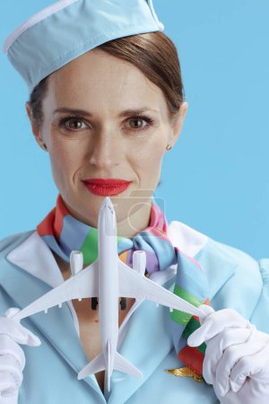 Téléchargez les photos : Élégante hôtesse de l'air sur fond bleu en uniforme bleu avec un petit avion. - en image libre de droit