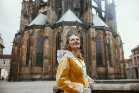 Photo for Happy young woman in yellow blouse and raincoat in Prague Czech Republic sightseeing. - Royalty Free Image