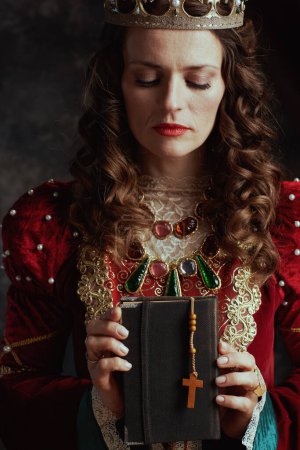 Photo for Medieval queen in red dress with book, rosary and crown. - Royalty Free Image