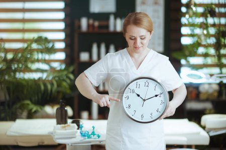 Téléchargez les photos : Temps de santé. massothérapeute féminine dans le salon de spa avec horloge. - en image libre de droit