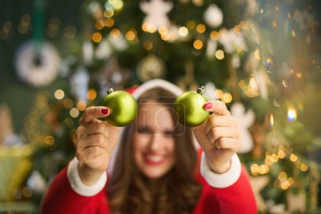 Photo for Christmas time. Closeup on woman with Santa hat and Christmas ball near Christmas tree in the living room. - Royalty Free Image