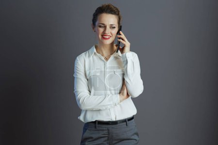Foto de Mujer de negocios con estilo feliz en blusa blanca usando un teléfono inteligente aislado sobre fondo gris. - Imagen libre de derechos