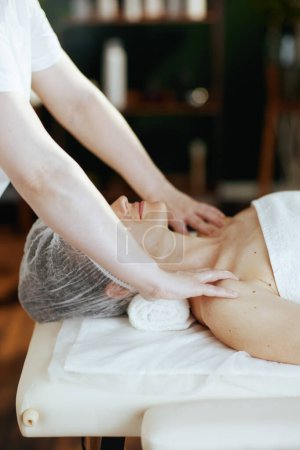 Téléchargez les photos : Temps de santé. massothérapeute dans l'armoire de massage massant les clients épaule sur table de massage. - en image libre de droit