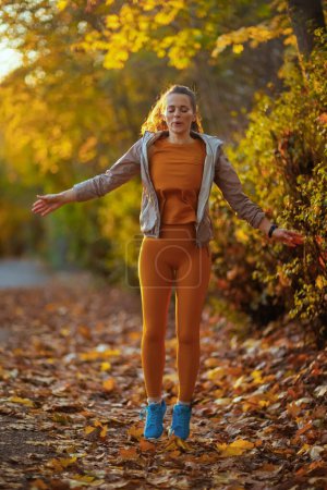 Foto de Hola otoño. Retrato de larga duración de la mujer con estilo en la ropa de fitness en el parque relajante después del entrenamiento. - Imagen libre de derechos