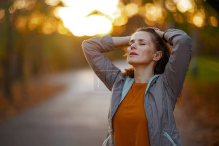 Photo for Hello autumn. relaxed fit woman in fitness clothes in the park relaxing after workout. - Royalty Free Image