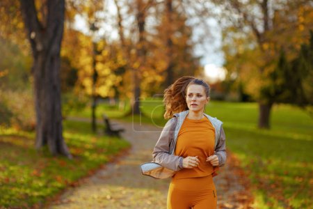 Photo for Hello autumn. modern woman in fitness clothes in the park jogging. - Royalty Free Image
