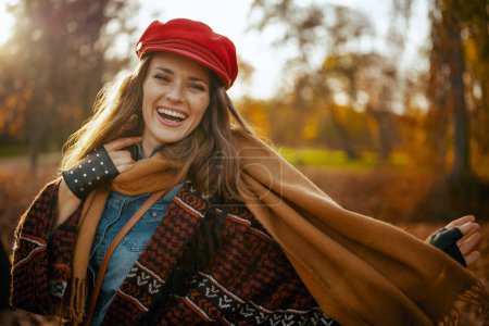 Photo for Hello autumn. Portrait of happy elegant 40 years old woman in red hat with scarf and gloves in the city park. - Royalty Free Image