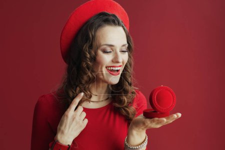 Foto de Feliz San Valentín. mujer elegante feliz en vestido rojo y boina sobre fondo rojo con joyero. - Imagen libre de derechos