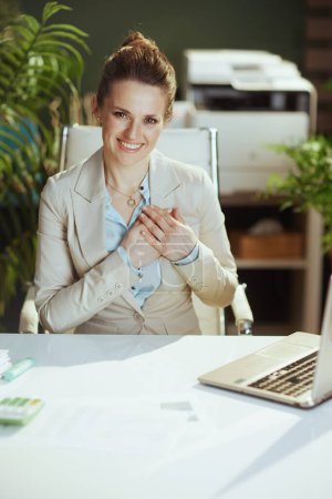 Foto de Retrato de la mujer trabajadora moderna feliz en un traje de negocios ligero en la oficina verde moderna con brazos cruzados en el pecho. - Imagen libre de derechos