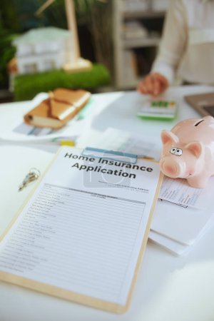Photo for Eco real estate business. Closeup on business woman in green office in white blouse with piggy bank, calculator, clipboard and document. - Royalty Free Image