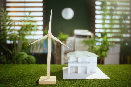 Téléchargez les photos : Des affaires durables. bureau en herbe dans un bureau vert moderne avec maison en papier et moulin à vent. - en image libre de droit