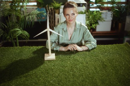 Photo for Eco trends. pensive elegant middle aged business woman in green blouse in modern green office with windmill - Royalty Free Image