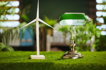 Photo for Time to go eco. grass desk in modern green office with windmill and lamp. - Royalty Free Image