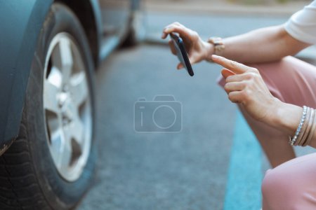 Téléchargez les photos : Accident de voiture. Gros plan sur voyageuse femme dans la ville avec smartphone prendre une photo près de la voiture avec pneu à plat. - en image libre de droit