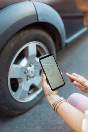 Photo for Car accident. Closeup on woman in the city with smartphone near car with flat tire. - Royalty Free Image