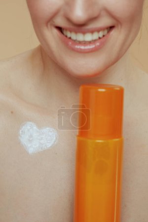 Photo for Closeup on modern middle aged woman with cosmetic cream jar and heart shaped cream on chest. - Royalty Free Image
