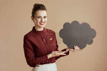 Photo for Happy stylish female air hostess against beige background with cloud shaped blackboard. - Royalty Free Image