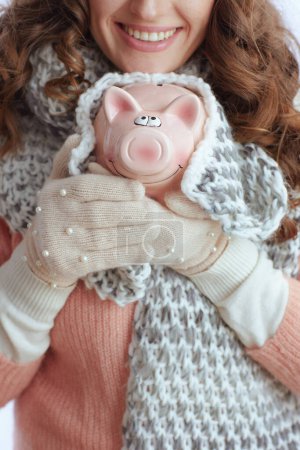 Photo for Hello winter. Closeup on trendy female in sweater, mittens, hat and scarf with piggy bank isolated on white. - Royalty Free Image