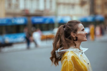 Téléchargez les photos : Femme élégante détendue en chemisier jaune et imperméable à Prague République tchèque sur la station de tram et à pied. - en image libre de droit