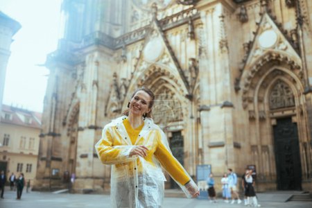 Foto de Feliz viajero solista de moda mujer en blusa amarilla y impermeable en Praga República Checa explorar atracciones. - Imagen libre de derechos