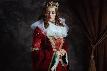 Foto de Reina medieval en vestido rojo con cuello blanco y corona sobre fondo gris oscuro. - Imagen libre de derechos