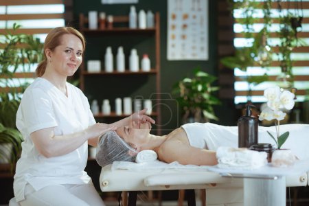 Téléchargez les photos : Temps de santé. massothérapeute dans le salon de spa masser le visage des clients sur la table de massage. - en image libre de droit