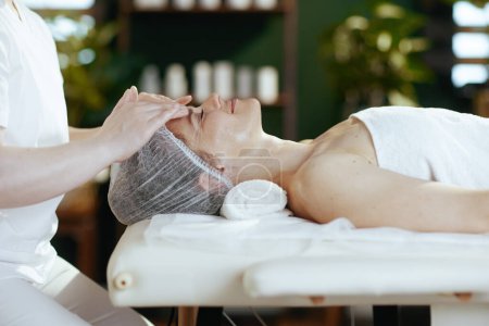 Foto de Tiempo de atención médica. masajista en gabinete de masajes masajeando a los clientes cara sobre mesa de masaje. - Imagen libre de derechos