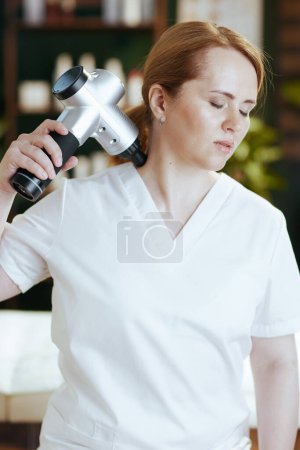 Photo for Healthcare time. female medical massage therapist in massage cabinet with massage pistol. - Royalty Free Image