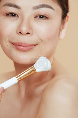 Téléchargez les photos : Young woman with makeup brush isolated on beige background. - en image libre de droit