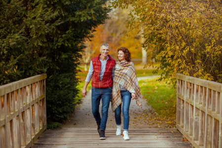 Téléchargez les photos : Bonjour l'automne. Portrait complet d'un couple romantique souriant dans le parc marchant sur le pont. - en image libre de droit