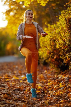 Téléchargez les photos : Bonjour l'automne. Portrait complet de la femme moderne de 40 ans en vêtements de fitness dans l'entraînement du parc. - en image libre de droit