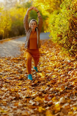 Foto de Hola otoño. joven mujer en ropa de fitness en el parque estiramiento. - Imagen libre de derechos