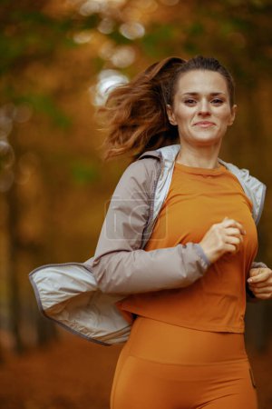 Foto de Hola otoño. en forma de mujer de mediana edad en ropa de fitness en el parque corriendo. - Imagen libre de derechos